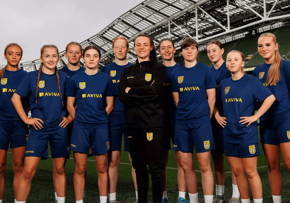 Group of girl football players with Irish football star Áine O’Gorman sporting Football Association of Ireland kits with the Aviva logo.