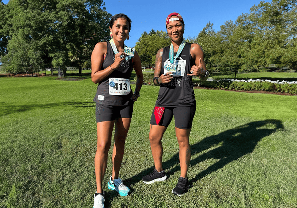 Jordan Daniel and Kali Reis stand in marathon running attire smiling. 