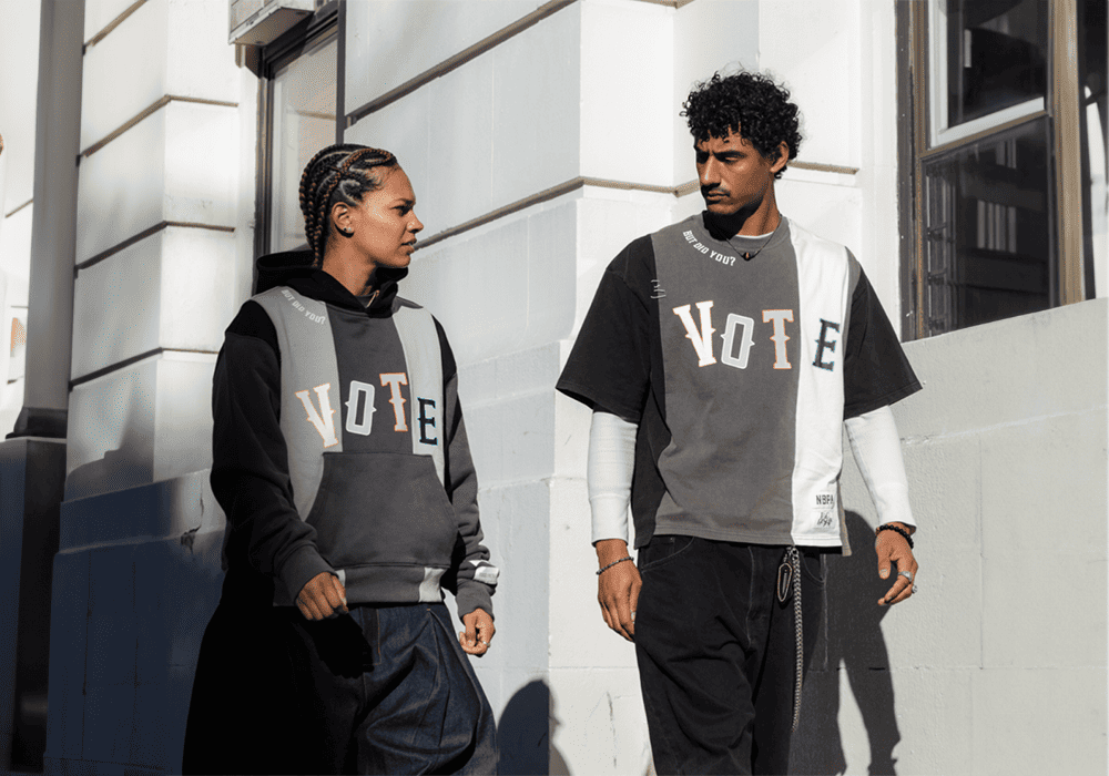 Two people walking down the street wearing top that reads 'Vote'